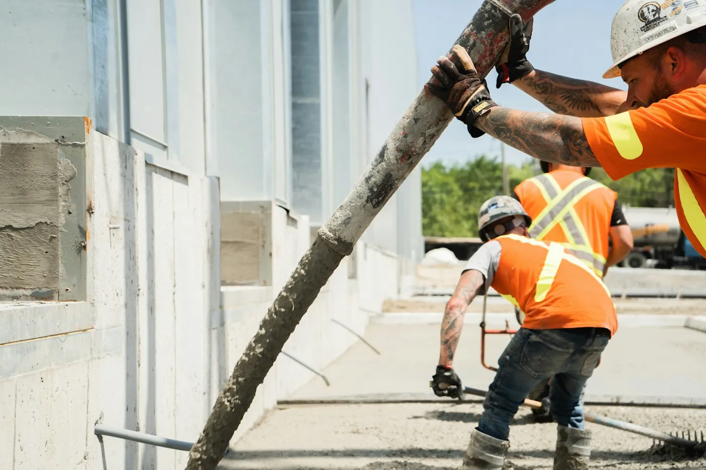 Muncitor turnând beton cu furtunul pompei